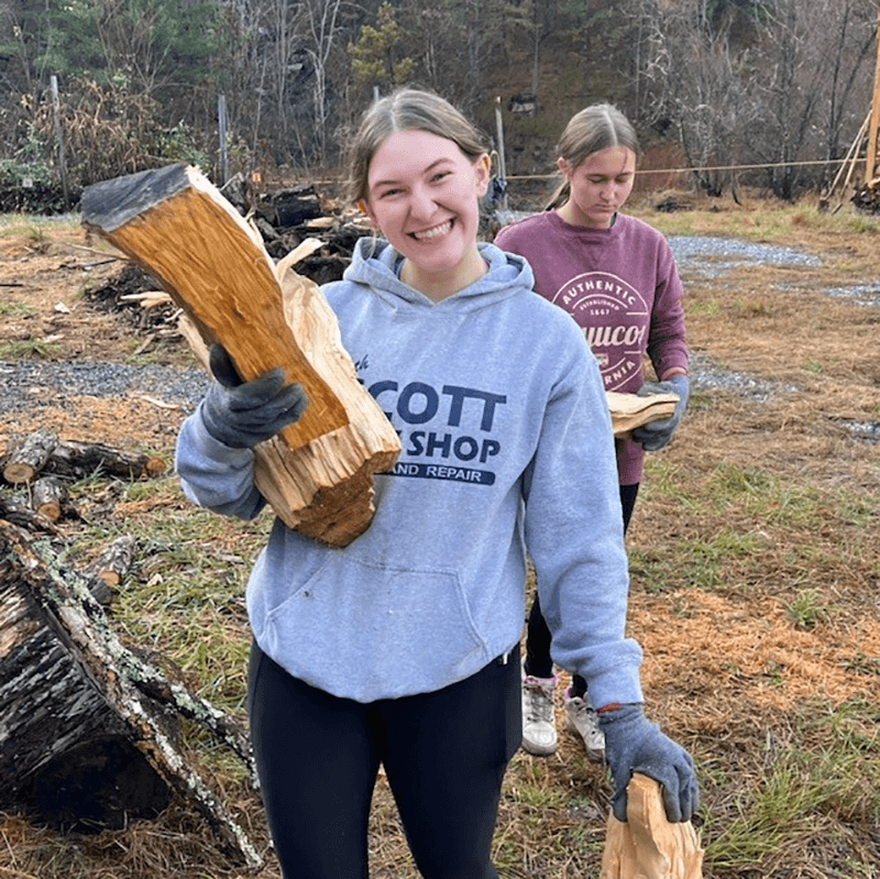 WCU student carries chopped wood for people in need
